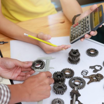 Engineer discussing and designing about mechanical gear parts in office.